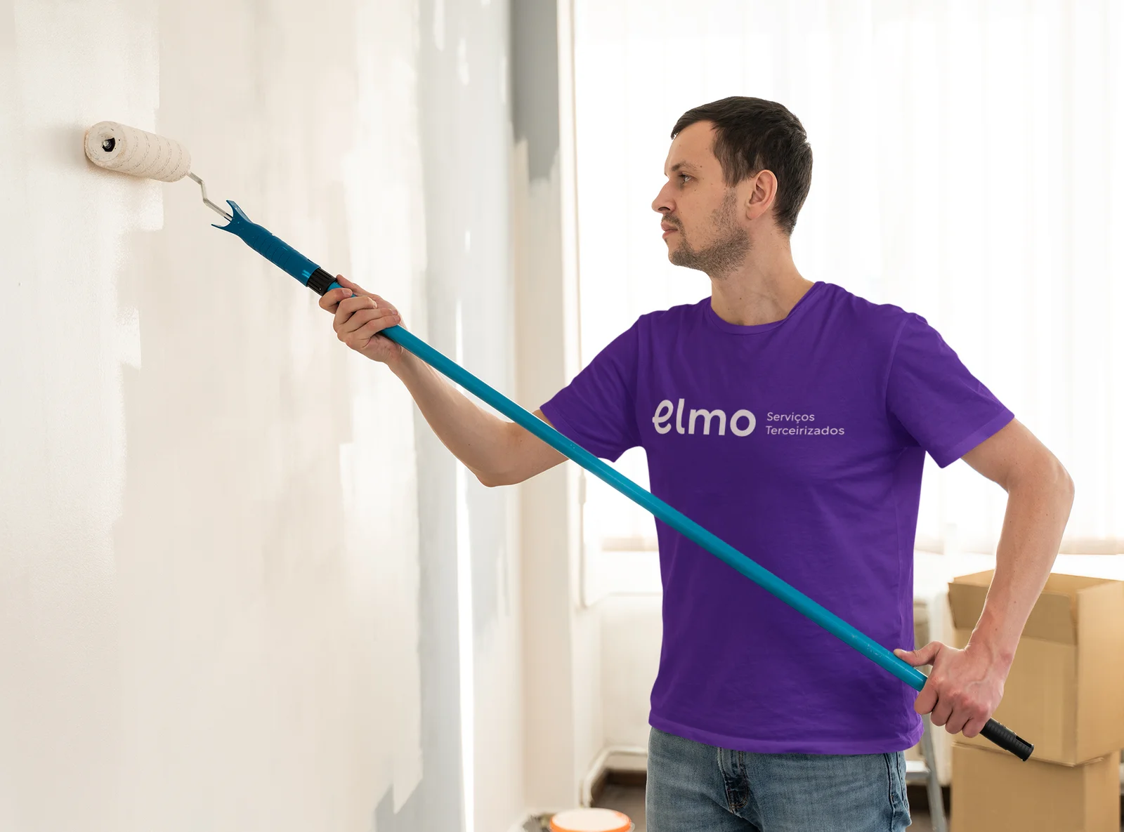 Profissional com camiseta Elmo pintando uma parede.